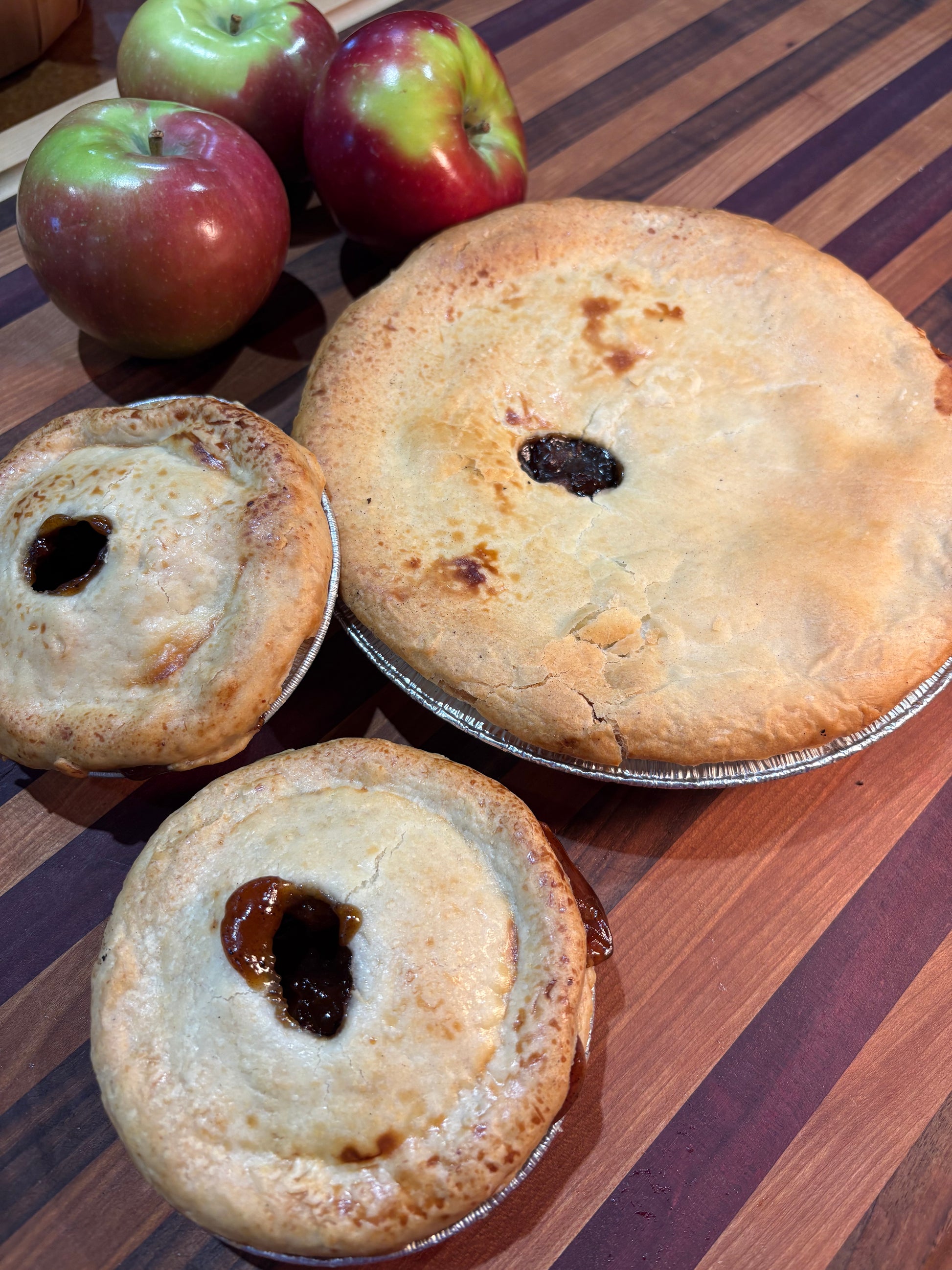 Three small pies with apple filling on a striped surface