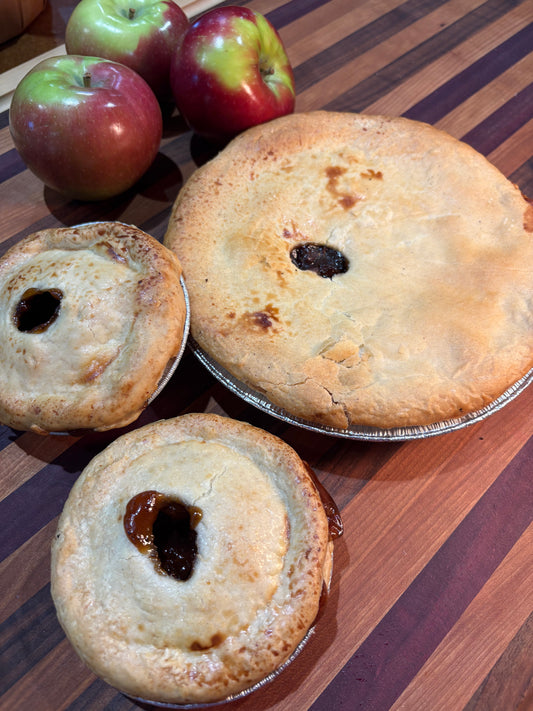 Three small pies with apple filling on a striped surface